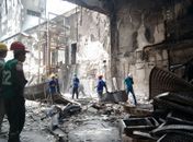 Técnicos retiram entulhos do interior de loja destruída por incêndio