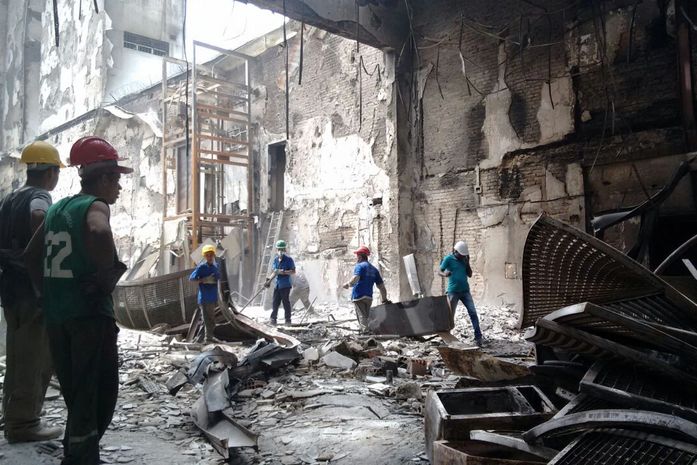 Técnicos retiram entulhos do interior de loja destruída por incêndio