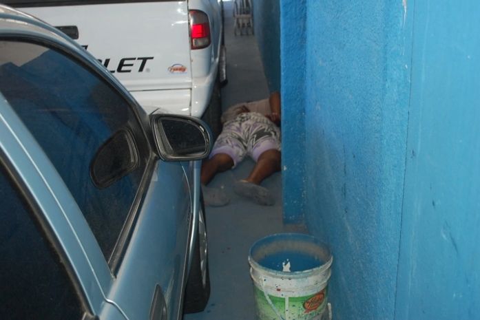 Corpo da vítima ficou caido entre um carro e a parede