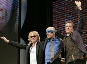 Mike Mills, Michael Stipe e Peter Buck, do R.E.M., acenam para o público ao fim de um show em Londres, em julho de 2005