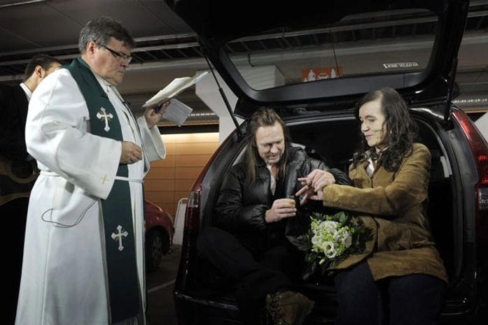 O noivo Juha-Ville Salin coloca a aliança na mão da amada, Merle Saksman, em casamento celebrado em um estacionamento de Helsinki
