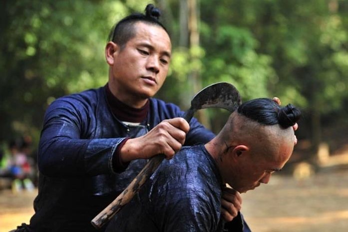 Homem usa foice para raspar cabelo de membro de aldeia na China