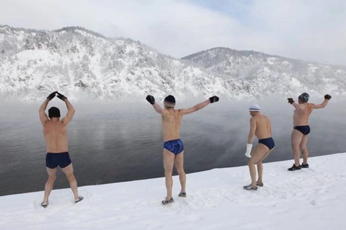 Russos se aquecem antes de nadar no rio.