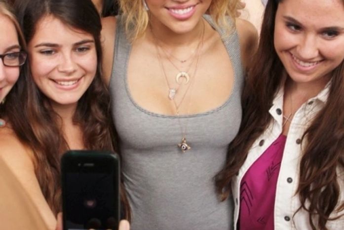 De vestido curto e justo, Miley Cyrus posa com fãs em Miami