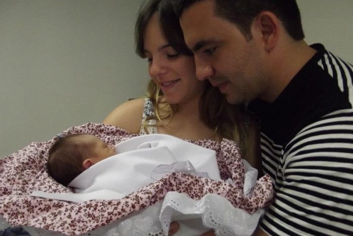Thaiane e Allan paparicando a filha na saída da maternidade