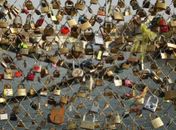 Cadeados que casais apaixonados prendem nas grades de uma ponte sobre o rio Sena
