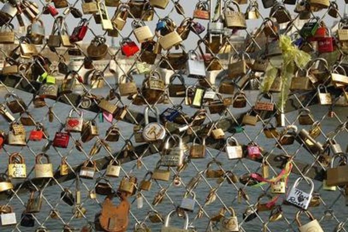 Cadeados que casais apaixonados prendem nas grades de uma ponte sobre o rio Sena