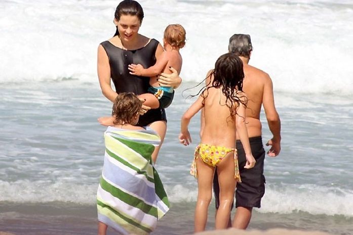 Com maiô comportado, Claudia Abreu mostra boa forma em praia em família