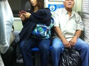 Sentada em um banco do vagão, ela checa o celular 