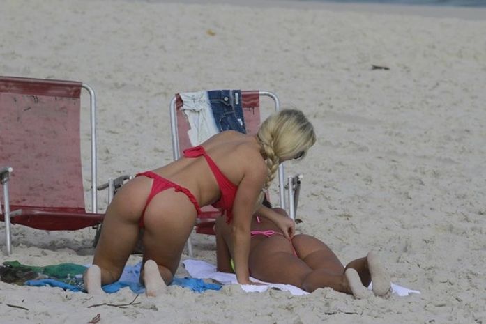 Ops! Caren Souza e Thaiz Schmitt ajeitam biquíni na praia