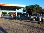 Bandidos assaltam posto de combustíveis, atiram em frentista e trocam tiros com policial