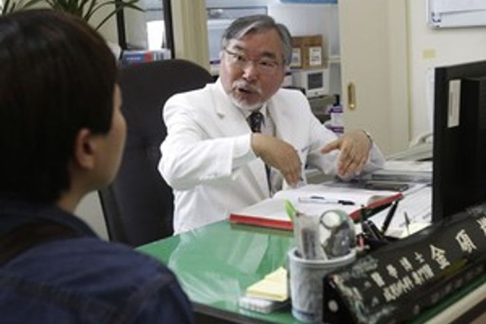O cirurgião Kim Seok-Kwun com um paciente em seu consultório