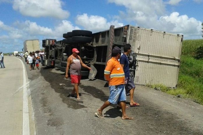 Motorista fica ferido após carreta com carga de biscoitos tombar na BR 101