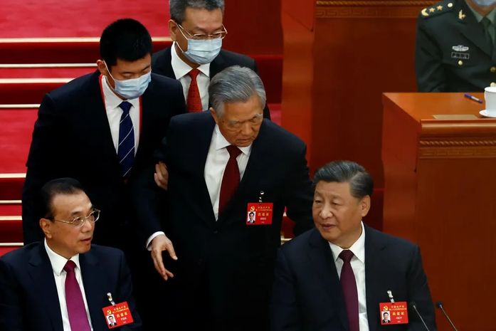 Imagens mostram Hu Jintao aparentemente relutando em sair, enquanto dois comissários o retiram do palco. Cena não foi exibida na transmissão oficial chinesa.