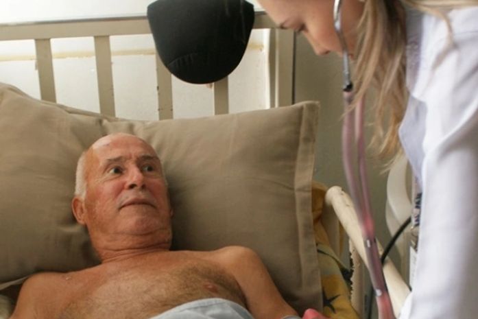 No conforto da sala da sua casa e em companhia da família, o aposentado João de Deus dos Santos, 91, recebe os cuidados do tratamento domiciliar