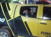 Mariana acena para populares de dentro da viatura da polícia, após ser resgatada.