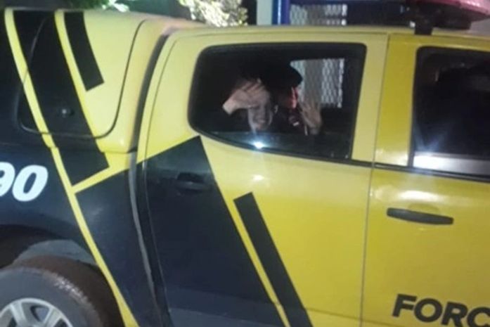 Mariana acena para populares de dentro da viatura da polícia, após ser resgatada.