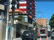 Após a colisão veículo capotou e parou, entre dois carros, em frete a saída de garagem de um edifício.