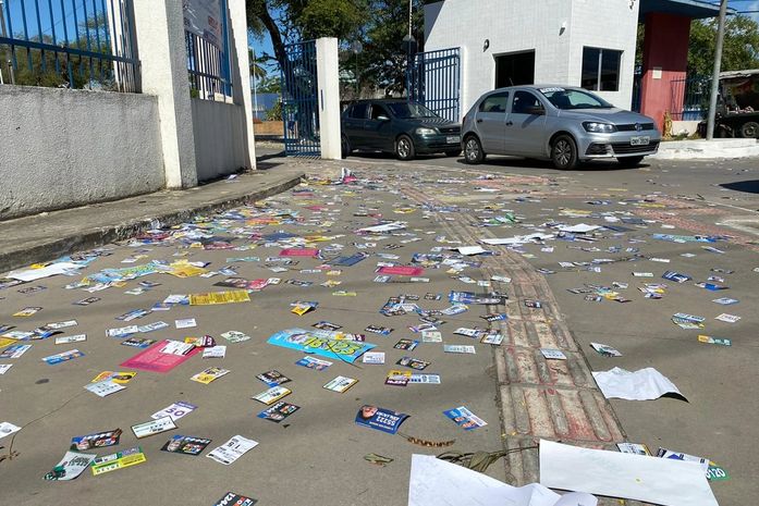 Candidatos ignoram lei eleitoral e sujam cidade com santinhos em frente aos locais de votação 