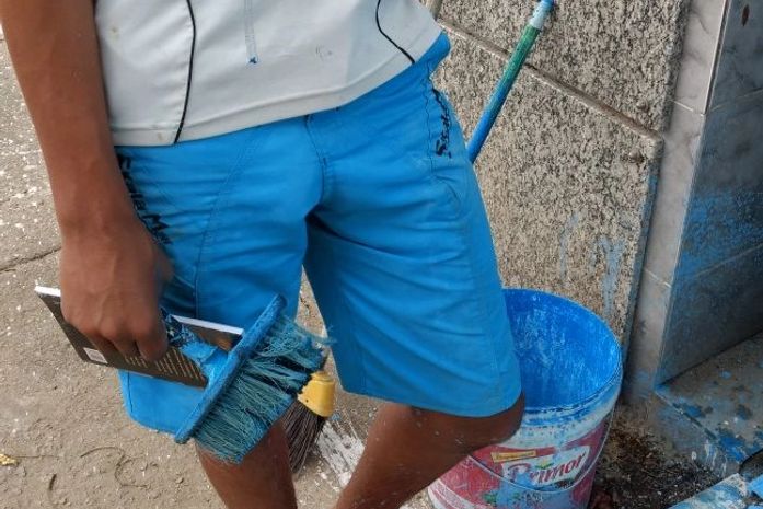 Adolescente limpando e pintando túmulos.