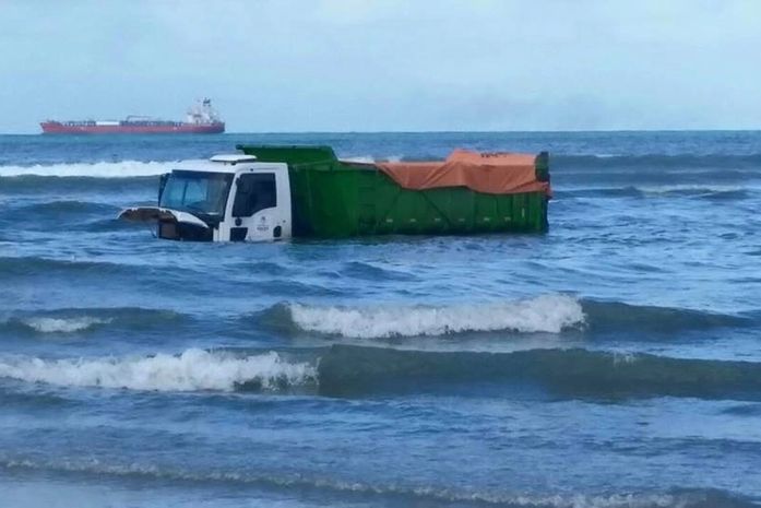 Caçamba de lixo fica parcialmente submersa em mar após pneu furar