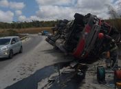 Caminhão com carga de cimento tomba e deixa motorista preso às ferragens na BR-101