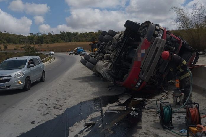 Caminhão com carga de cimento tomba e deixa motorista preso às ferragens na BR-101