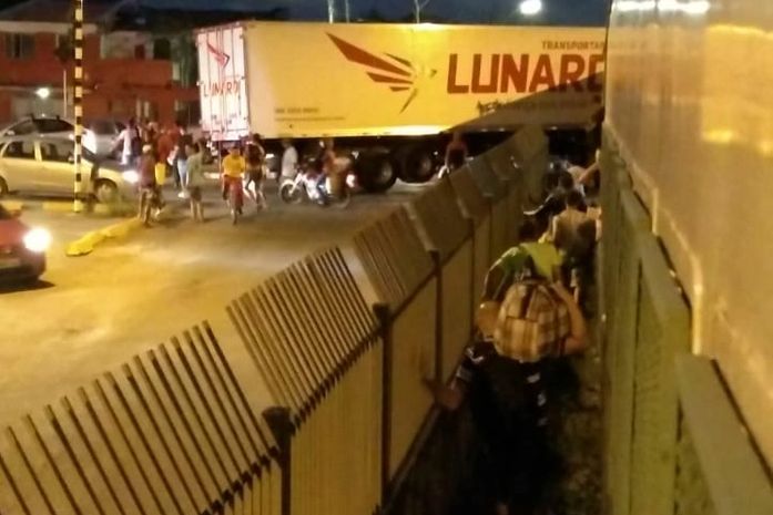 Pedestres passam pelo canal, embaixo da carreta que ficou suspensa.