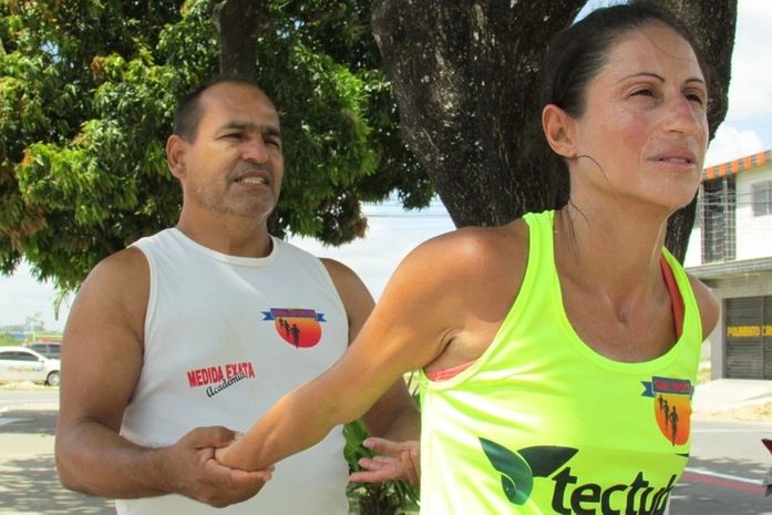O treinador Gerson Diniz auxilia a atleta durante a preparação física