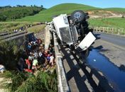 Carreta tomba e motorista fica preso às ferragens