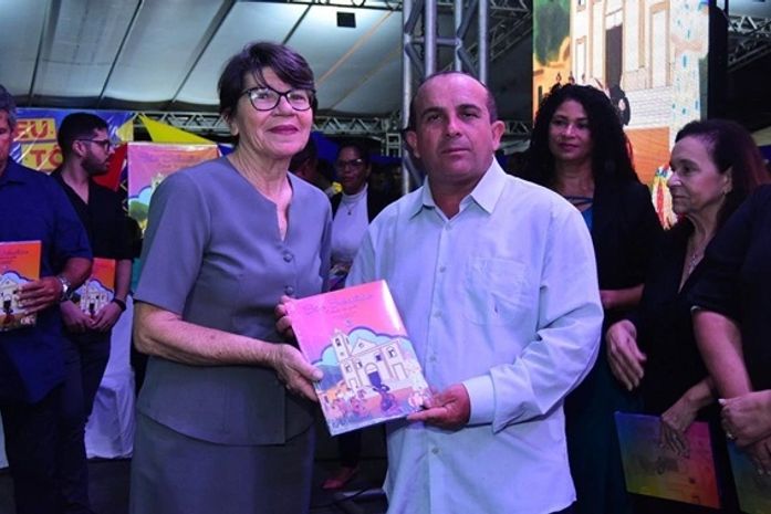 Professor Sinval de Jesus – um dos escritores do livro faz a entrega de um exemplar a rendeira Maria Severiano