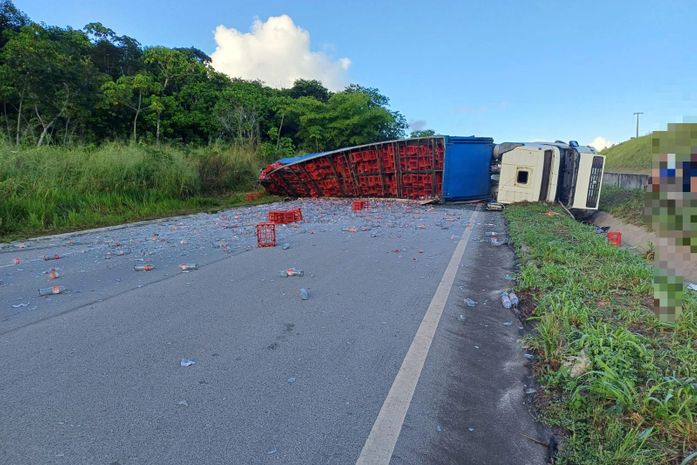 Carreta que transportava refrigerantes tomba e interdita parte da BR-101; pedaços de vidro ficam espalhados pela rodovia