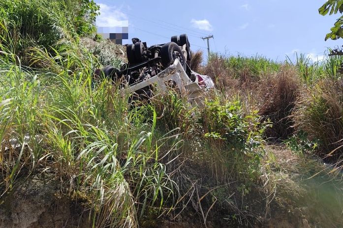 Após caminhão cair em ribanceira, bombeiros trabalham para resgatar vítima de dentro do veículo