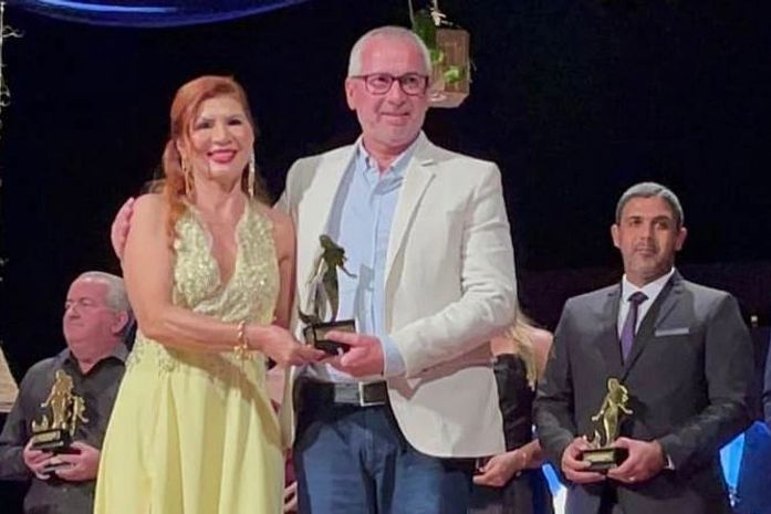 Maurício recebendo o troféu da coordenadora do evento Francis Núbia
