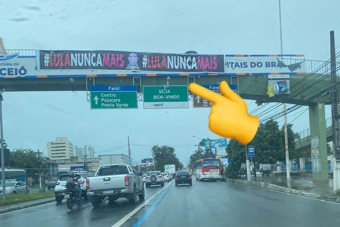 Opositores ao ex-presidente Lula fixam faixa na Avenida Fernandes Lima durante passagem por Alagoas