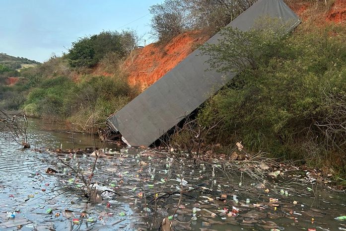 Carreta tomba e cabine fica imersa em açude, na rodovia AL-115